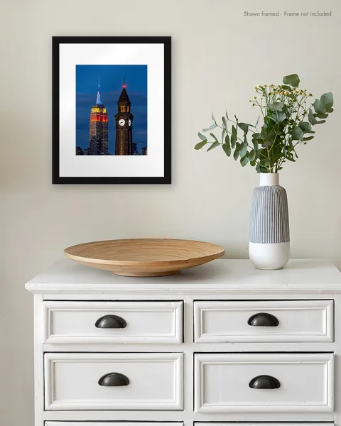 Empire State of Time, matted, shown in a black frame on a wall above a white dresser
