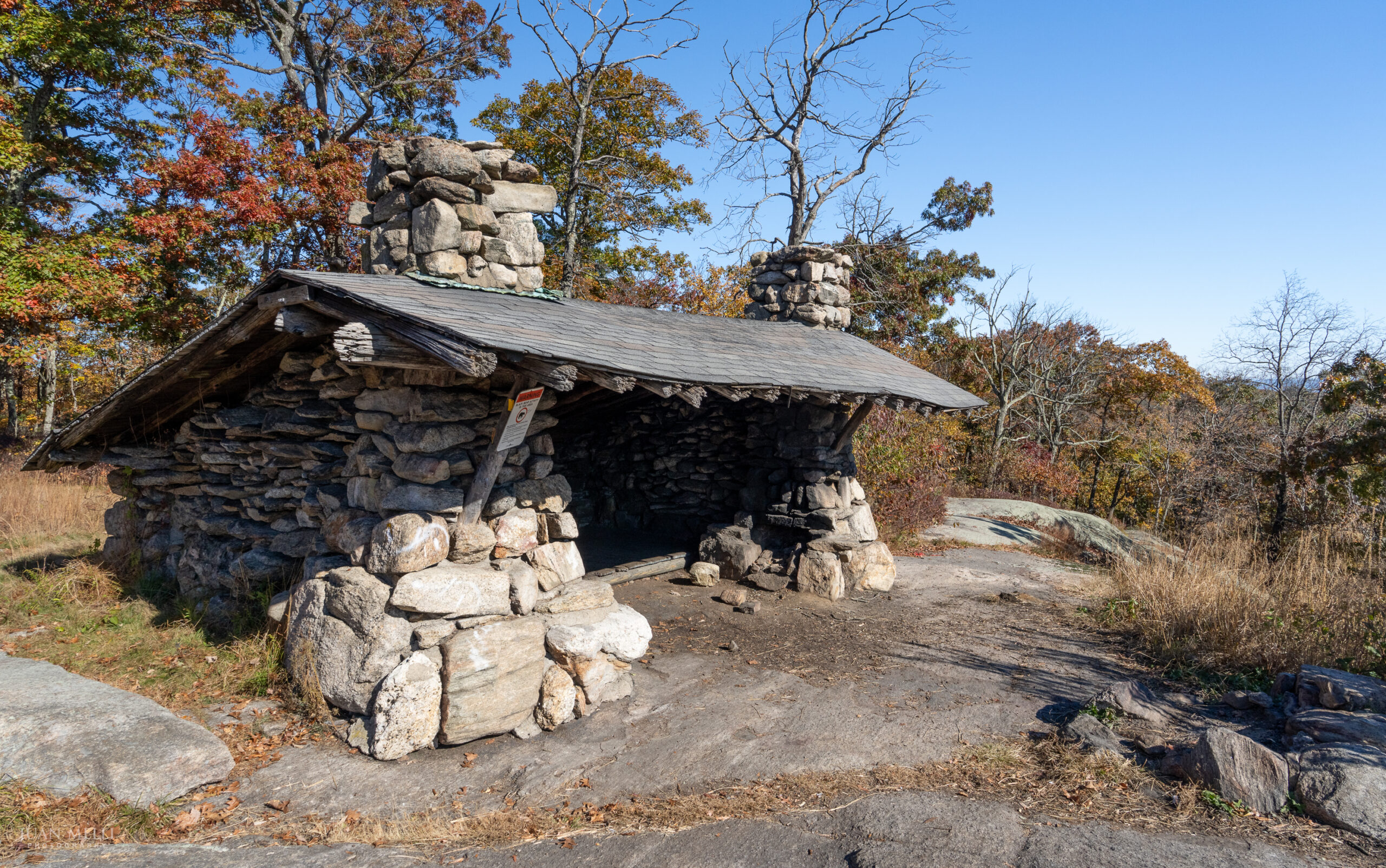 Big Hill Shelter, a stone lean-to with two stone chimneys, on a rock outcrop in Harriman State Park