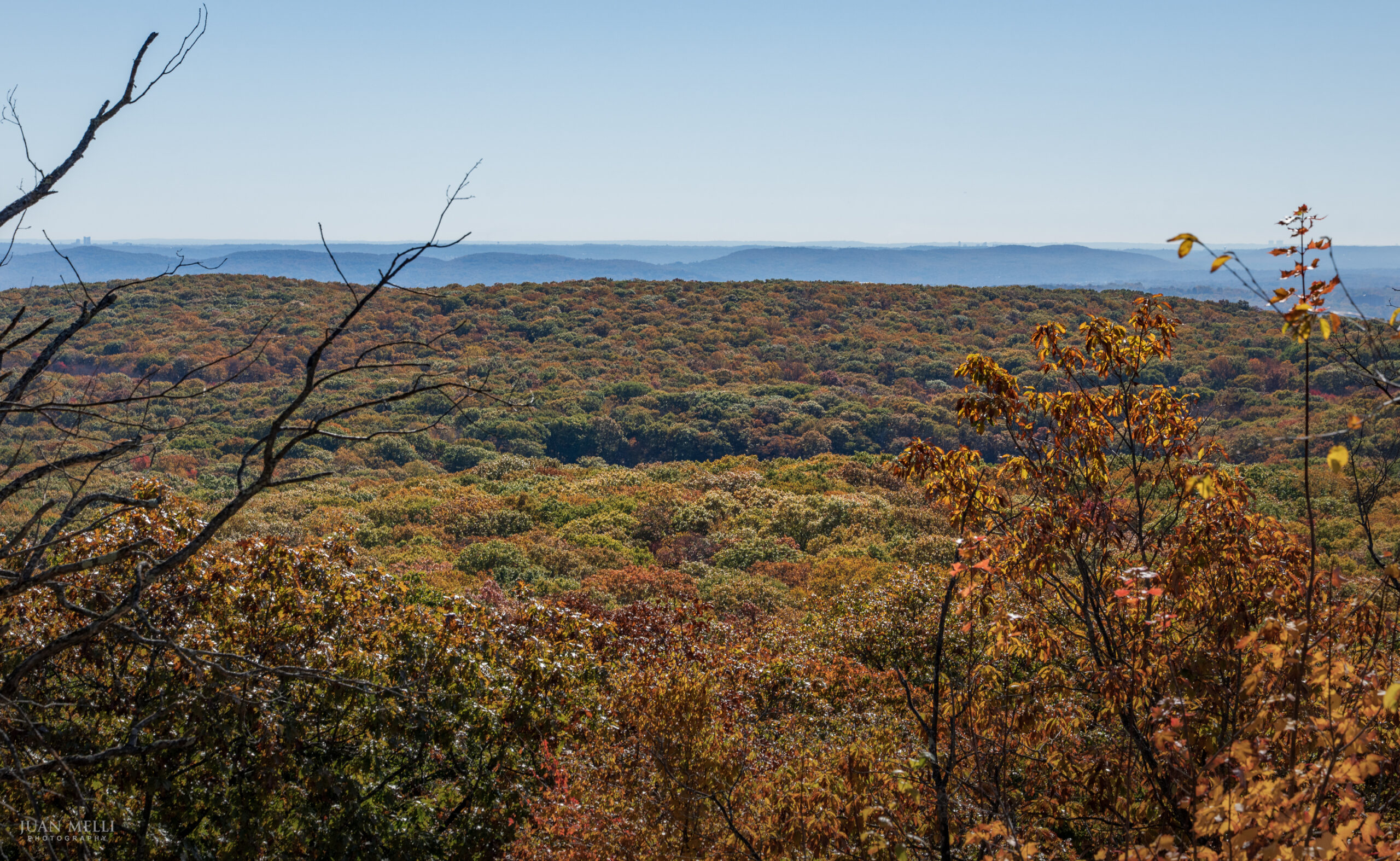 View from near Big Hill Shelter over rolling hills in fall color, fading to a hazy horizon