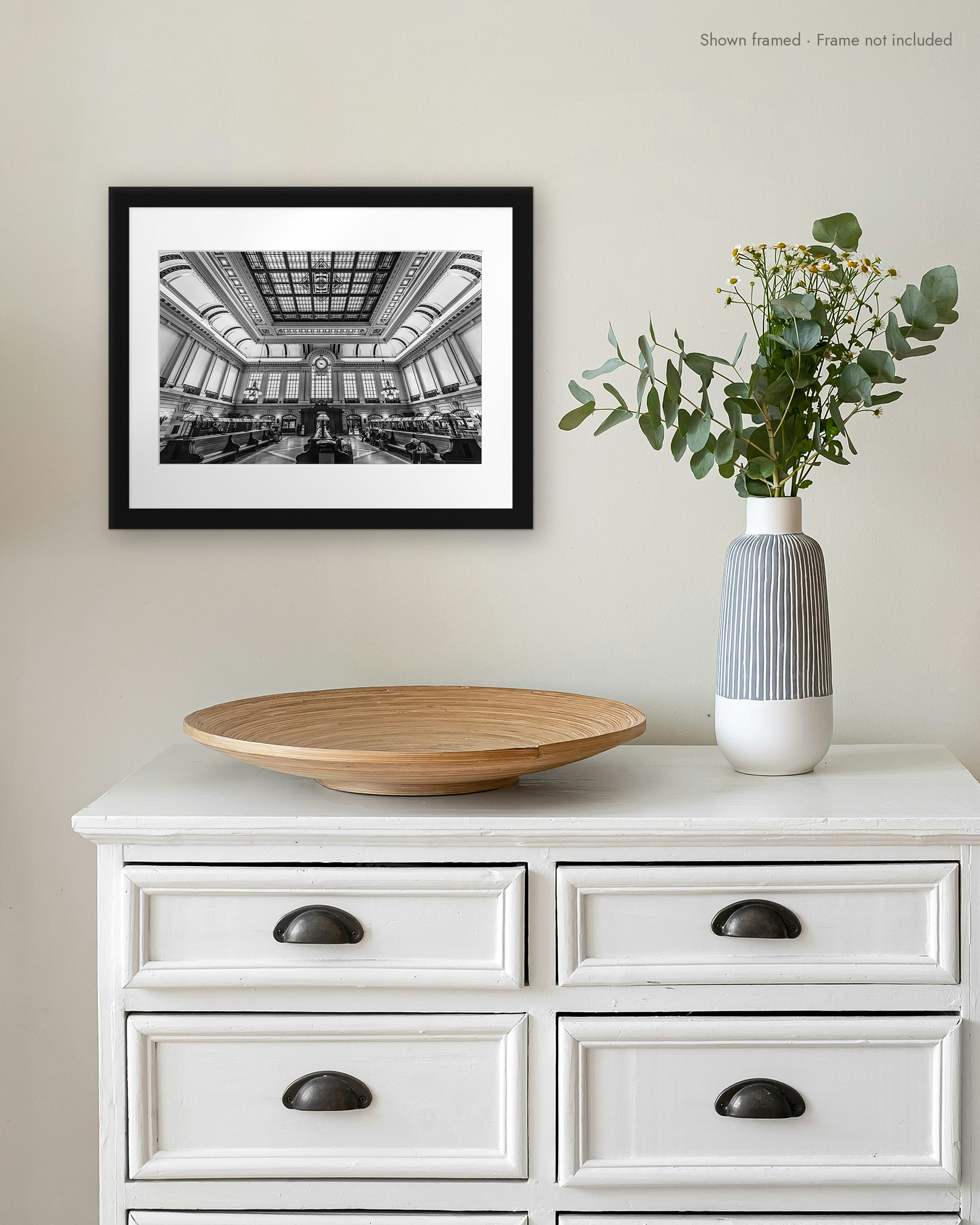 Waiting Room print in a white mat and black frame on a wall above a white dresser