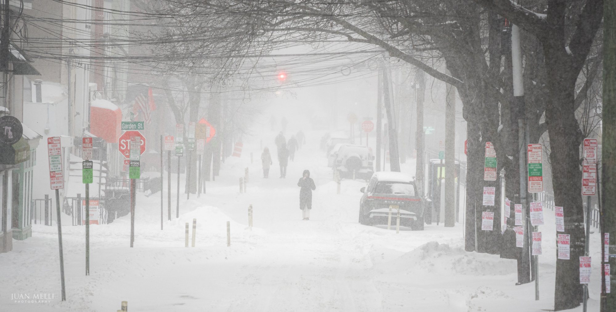 Pedestrians walk along 4th Street, an Emergency Snow Route, covered in No Parking signs