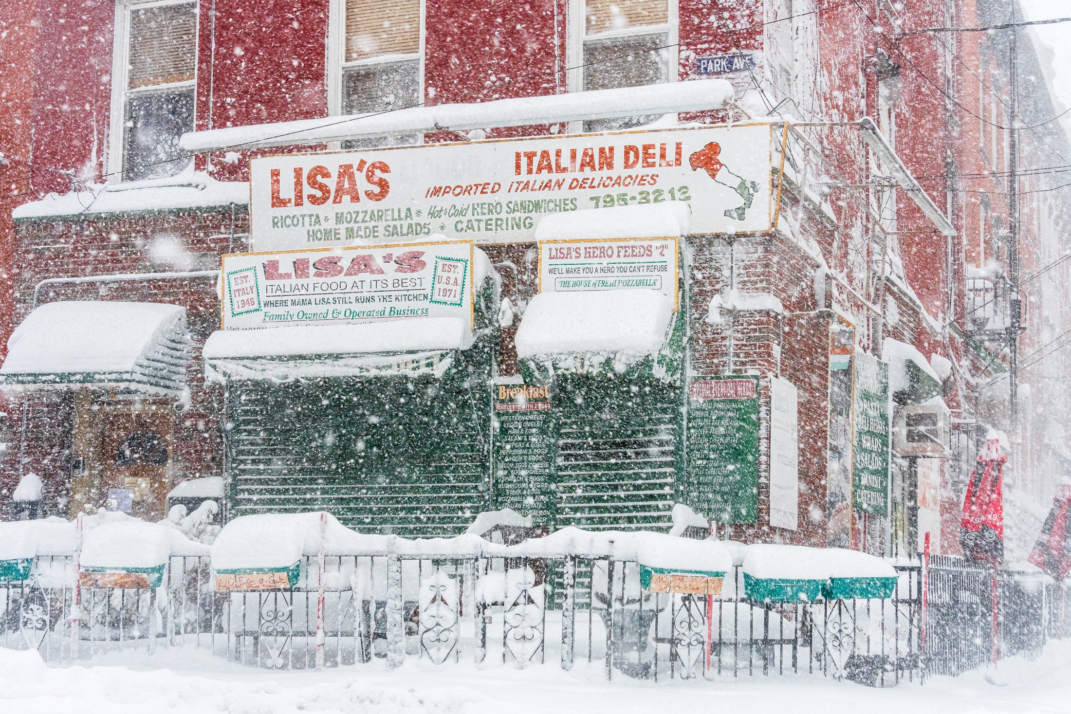 Photograph of Lisa’s Italian Deli in Hoboken during the Blizzard of 2026, its shutters closed and its signs and awnings heavy with snow.
