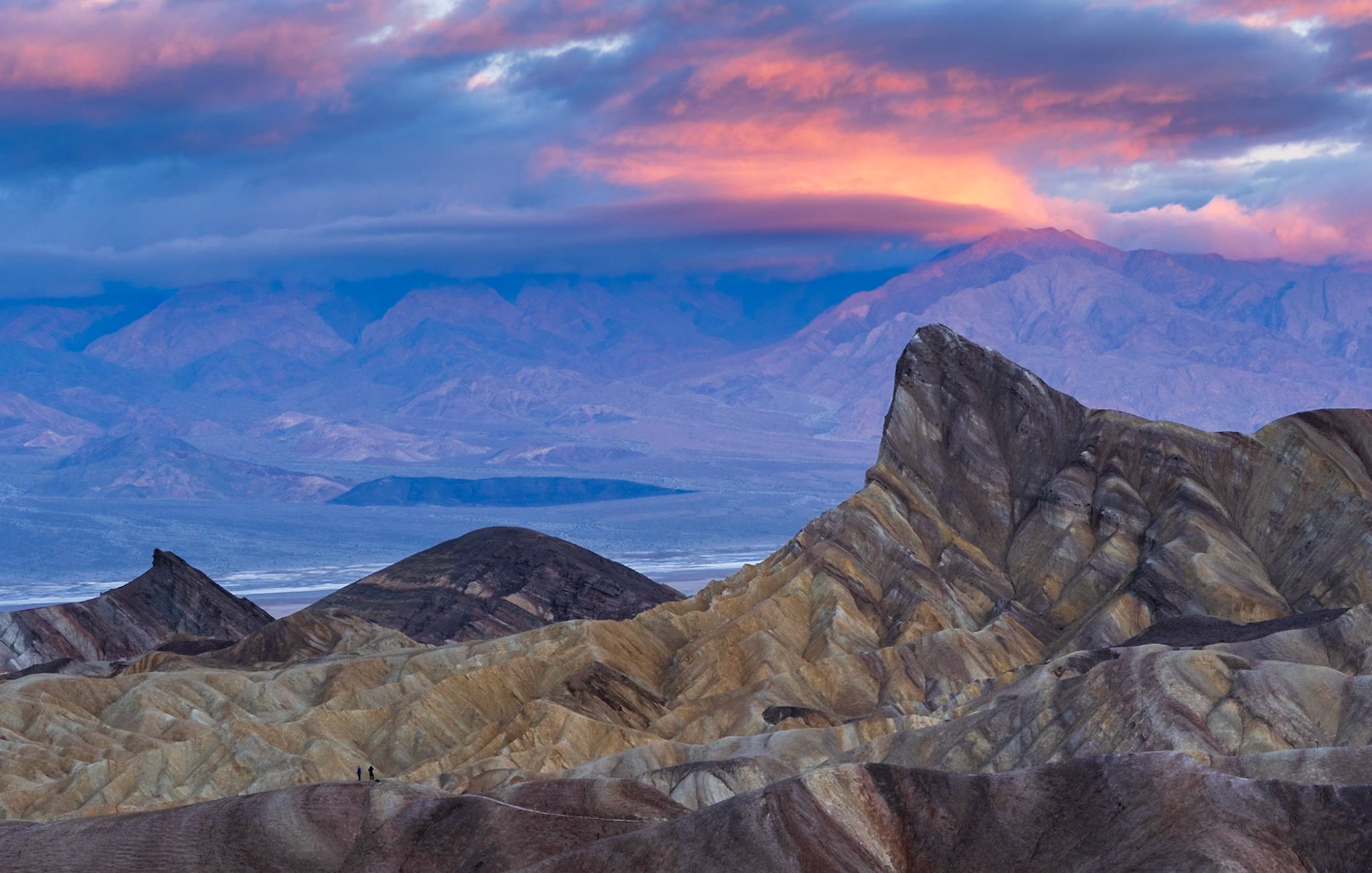 The golden badlands of Zabriskie Point in Death Valley under pink clouds