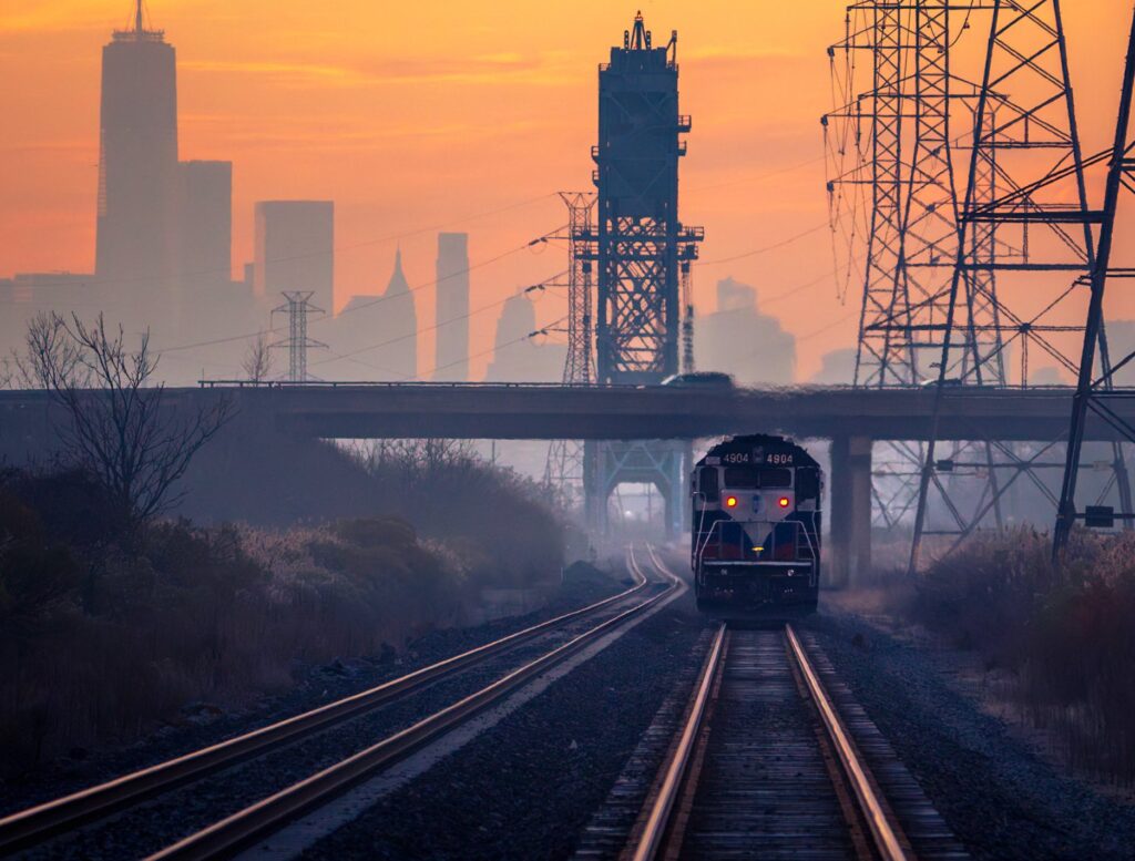 A freight train rolling out of morning haze in the Meadowlands, a lift bridge and the Manhattan skyline behind