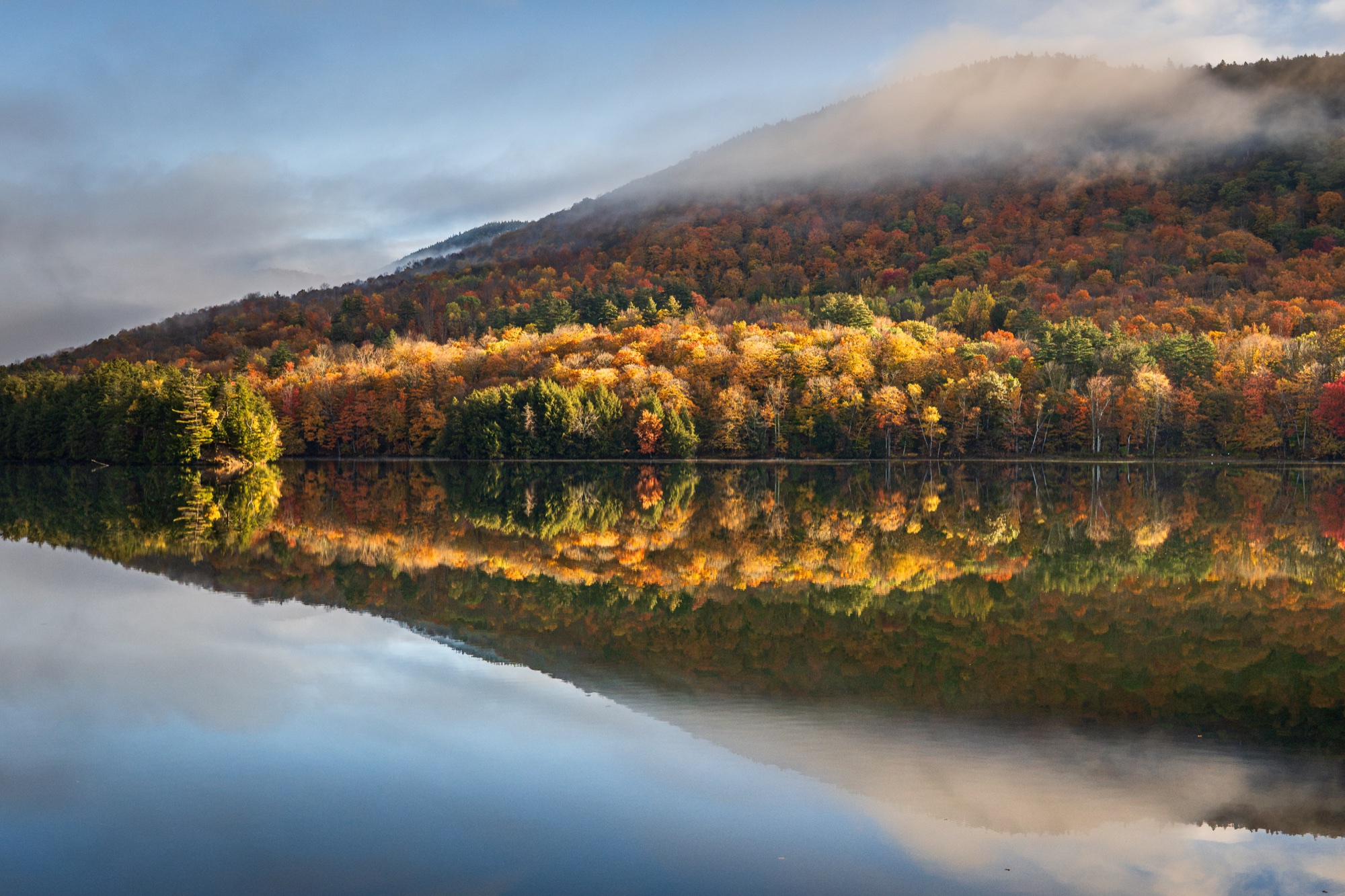 Photograph of peak fall color and a lifting cloud bank reflected in Woodward Reservoir along Route 100 in Vermont.