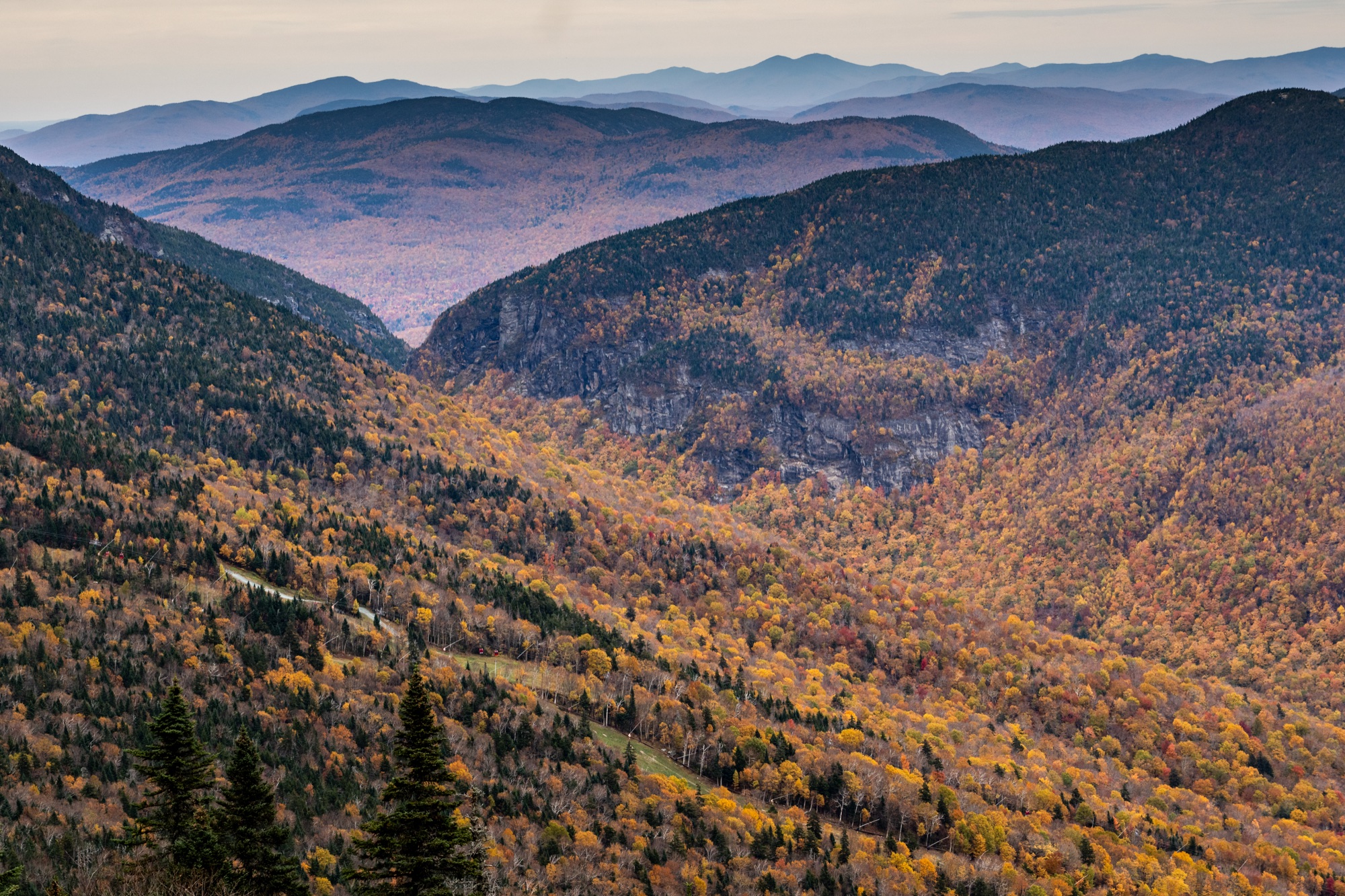 Smugglers' Notch in fall color beneath rocky cliffs, seen from Mount Mansfield